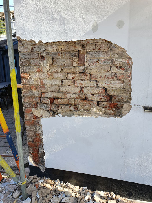 Failed render being repaired on a public house
