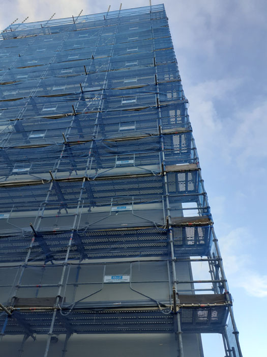 Scaffolding with debris netting erected prior to concrete repairs on a high rise office block